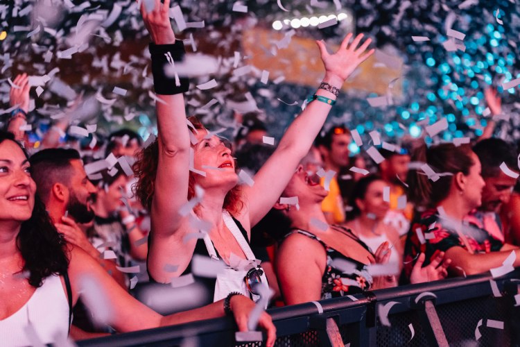 Una chica en un concierto con las manos levantadas.